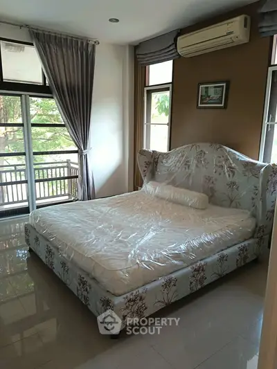 Spacious bedroom with elegant decor and large windows overlooking greenery.