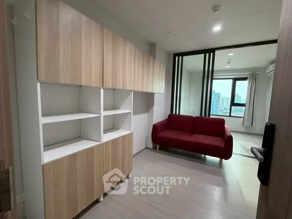 Modern apartment interior with stylish wooden cabinets and a cozy red sofa, offering a bright and inviting atmosphere.