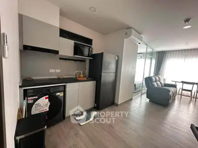 Modern apartment interior with kitchen, living area, and washing machine, featuring sleek design and natural light.