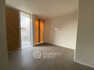 Spacious empty room with large windows and wooden flooring, perfect for customization.