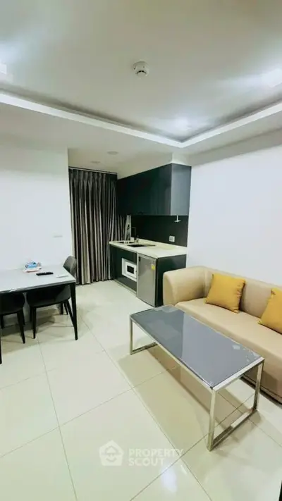 Modern open-layout living room with sleek kitchen and cozy seating area.