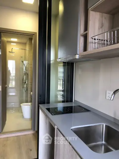 Modern compact kitchen with sleek design and adjacent bathroom in a stylish apartment.