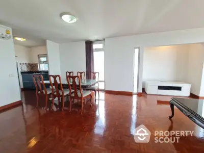 Spacious dining area with elegant wooden flooring and modern furniture in open layout apartment.