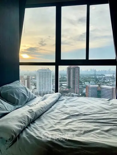 Stunning bedroom with panoramic city view through large windows at sunset.