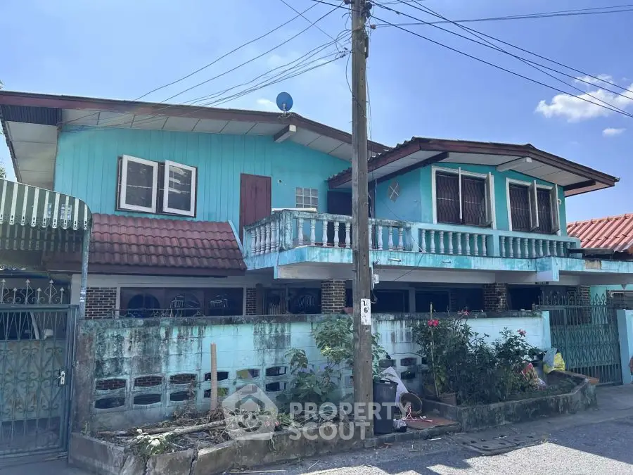 Charming blue two-story house with balcony and garden in a serene neighborhood.