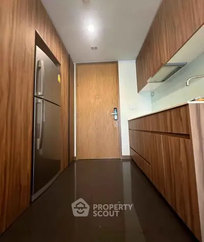 Modern kitchen with sleek wooden cabinetry and stainless steel appliances in a stylish apartment.