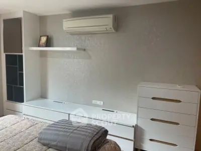 Modern bedroom with sleek white furniture and air conditioning unit, perfect for comfort and style.