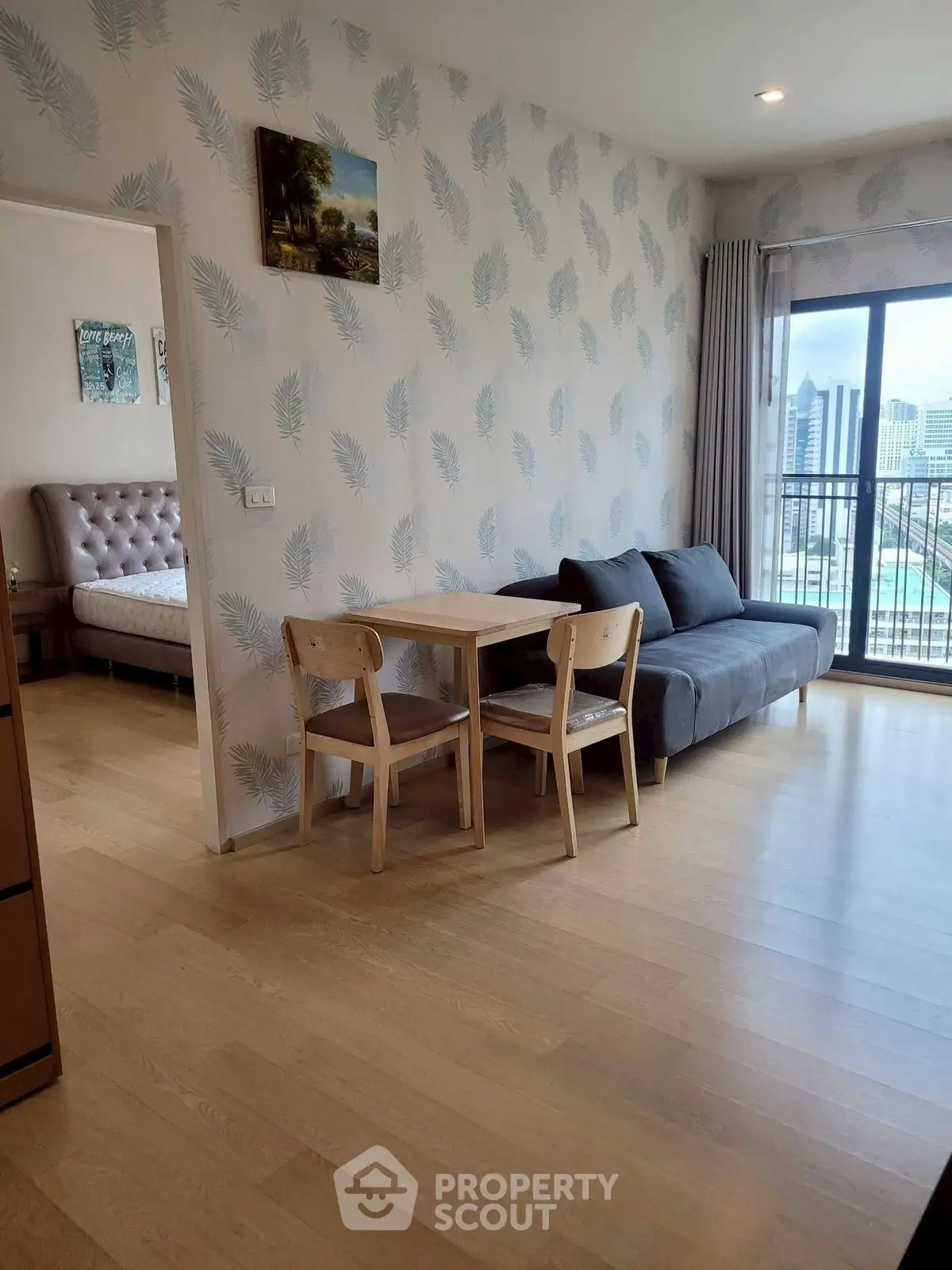 Modern living room with wooden flooring, cozy sofa, dining table, and city view balcony.