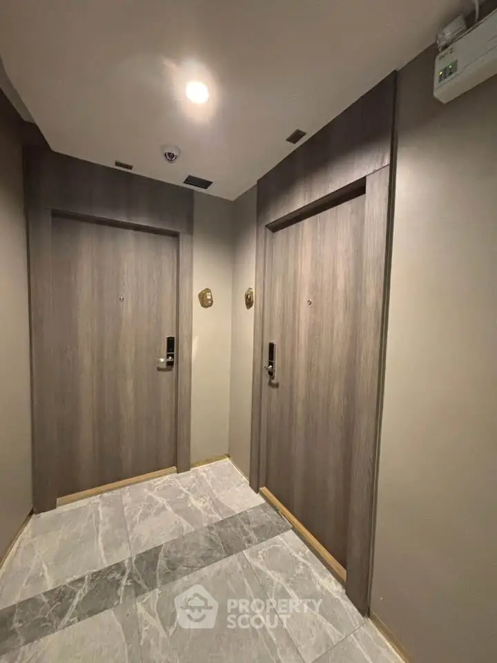 Modern apartment building hallway with sleek wooden doors and marble flooring.