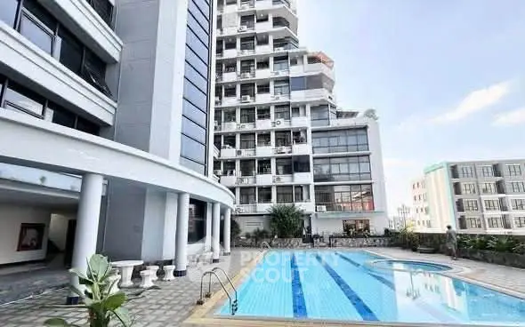 Modern apartment building with outdoor swimming pool and spacious deck area.