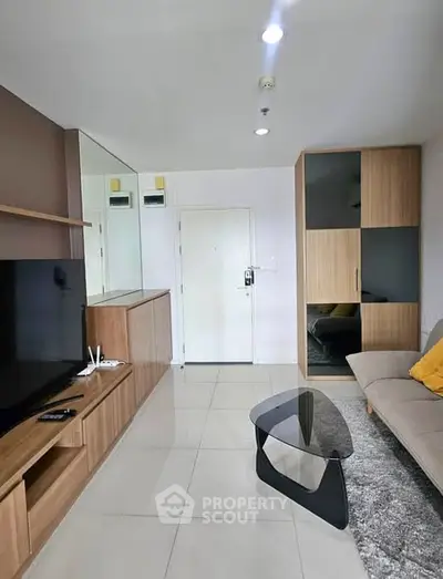 Modern living room with sleek furniture and large TV in a stylish apartment.