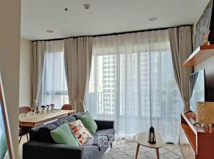Modern living room with large windows and stylish decor in a high-rise apartment.