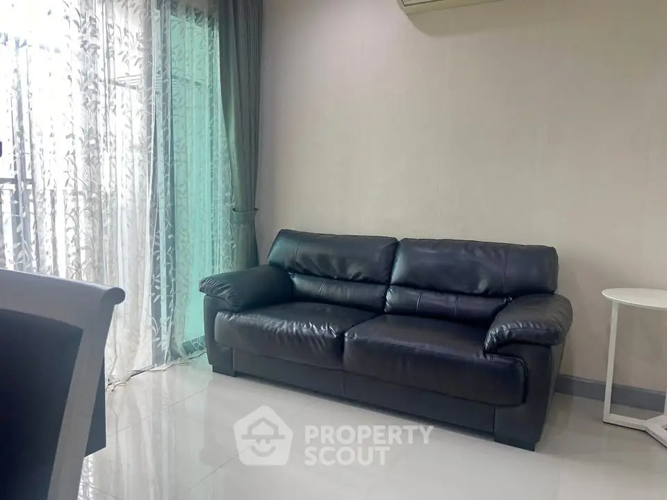 Modern living room with sleek black leather sofa and elegant curtains, perfect for stylish urban living.