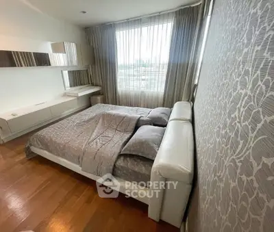 Spacious bedroom with elegant decor and large window offering natural light.