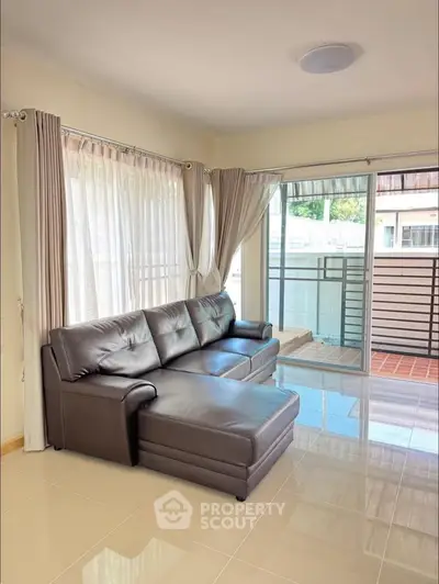 Spacious living room with leather sofa and large windows for natural light