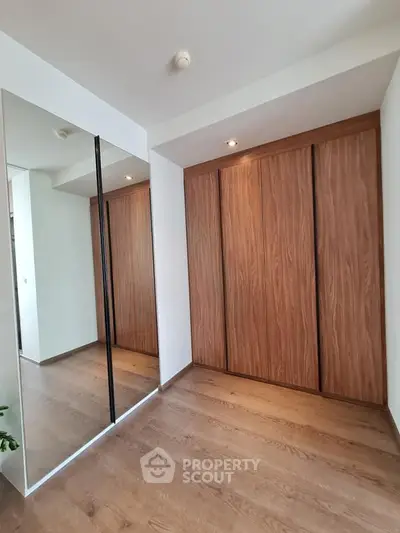 Spacious modern bedroom with wooden flooring and large mirrored wardrobe doors.