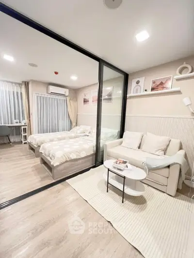 Modern studio apartment with cozy living area and stylish bedroom separated by glass partition.