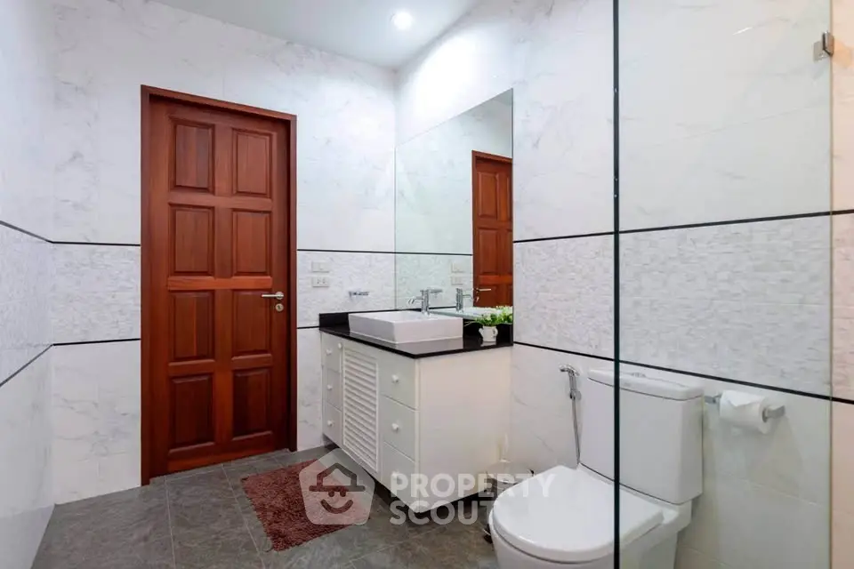Modern bathroom with elegant marble tiles and wooden door