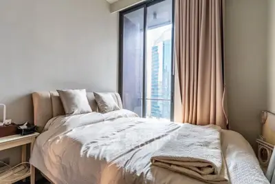 Cozy bedroom with city view, featuring a comfortable bed and large window for natural light.