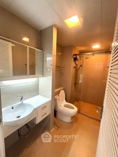 Modern bathroom with sleek fixtures and glass shower enclosure in a contemporary apartment.