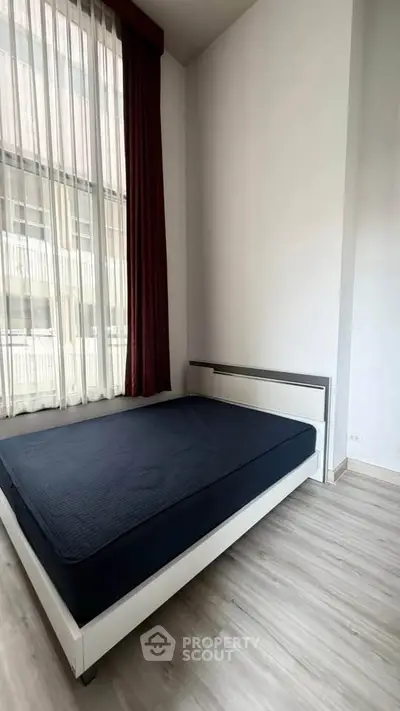 Modern bedroom with large window and minimalist design, featuring a sleek bed and stylish flooring.