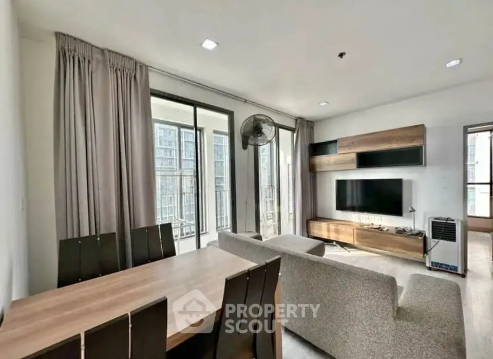 Spacious modern living room with large windows and stylish furniture in a high-rise apartment.