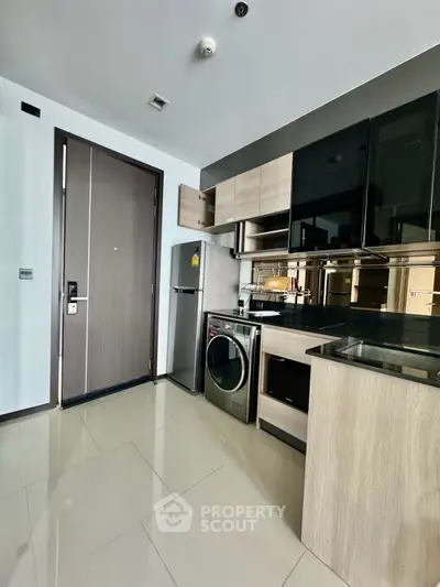 Modern kitchen with sleek appliances and wood cabinetry in a stylish apartment.