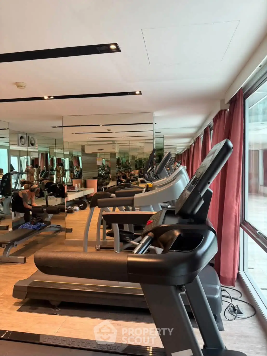 Modern gym with state-of-the-art equipment and large mirrors in a luxury building.