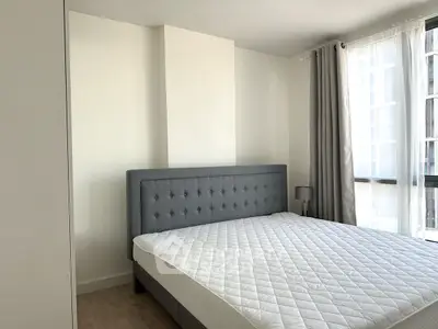 Modern bedroom with stylish grey headboard and large window for natural light.