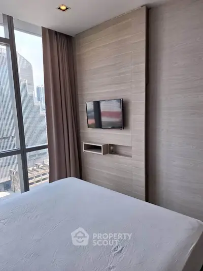 Modern bedroom with city view, featuring sleek design and wall-mounted TV, perfect for urban living.
