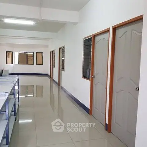 Spacious corridor with multiple doors and tiled flooring in a modern building.