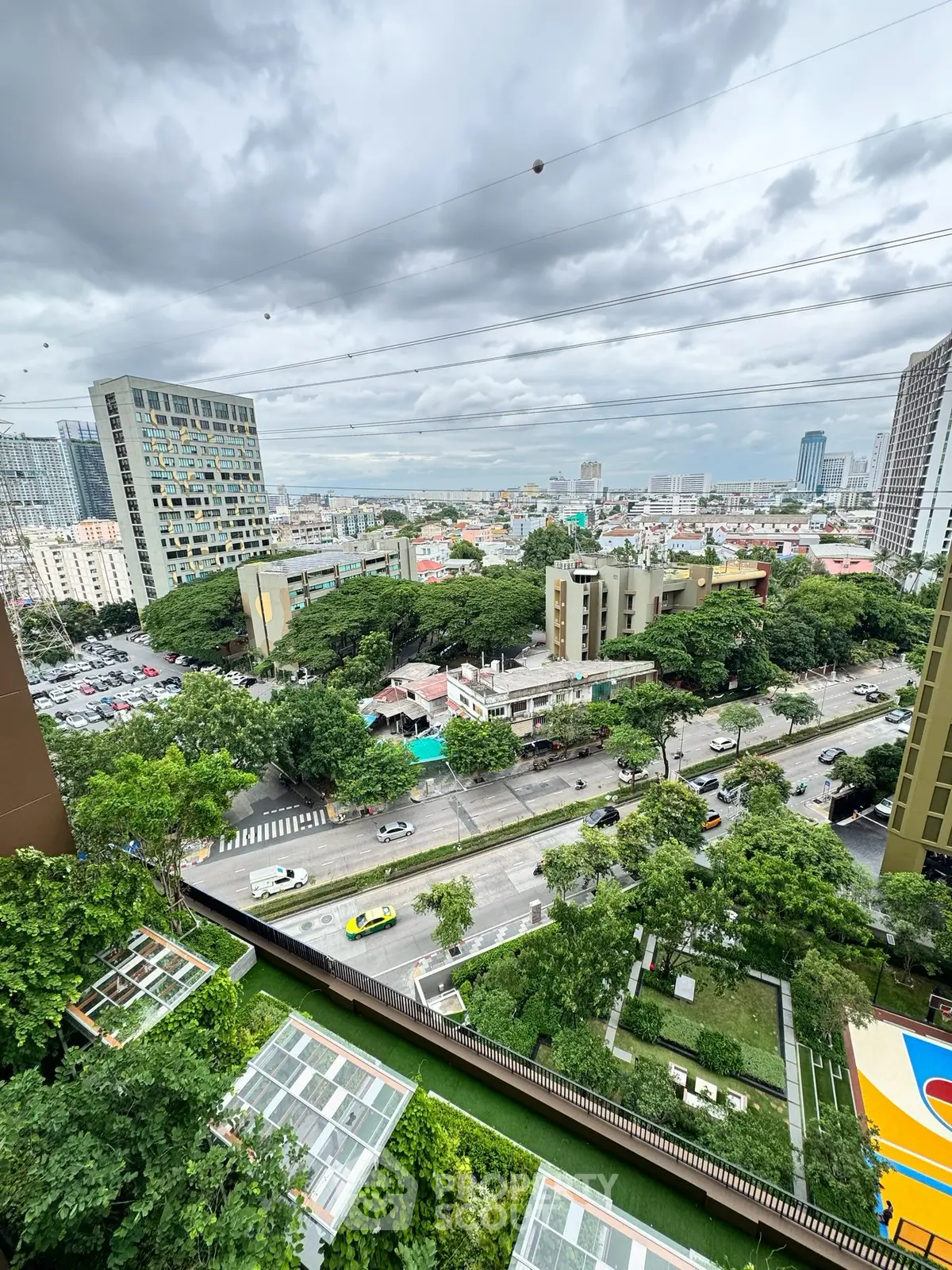 Stunning cityscape view from high-rise building with lush greenery and urban skyline.