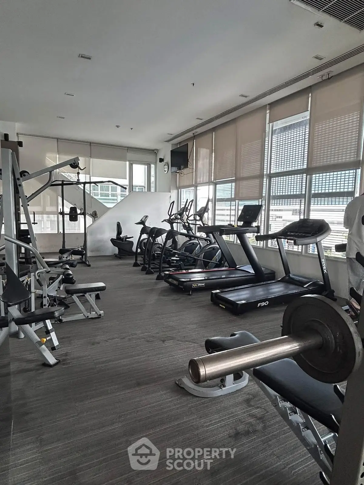 Modern gym with state-of-the-art equipment and large windows in a residential building.