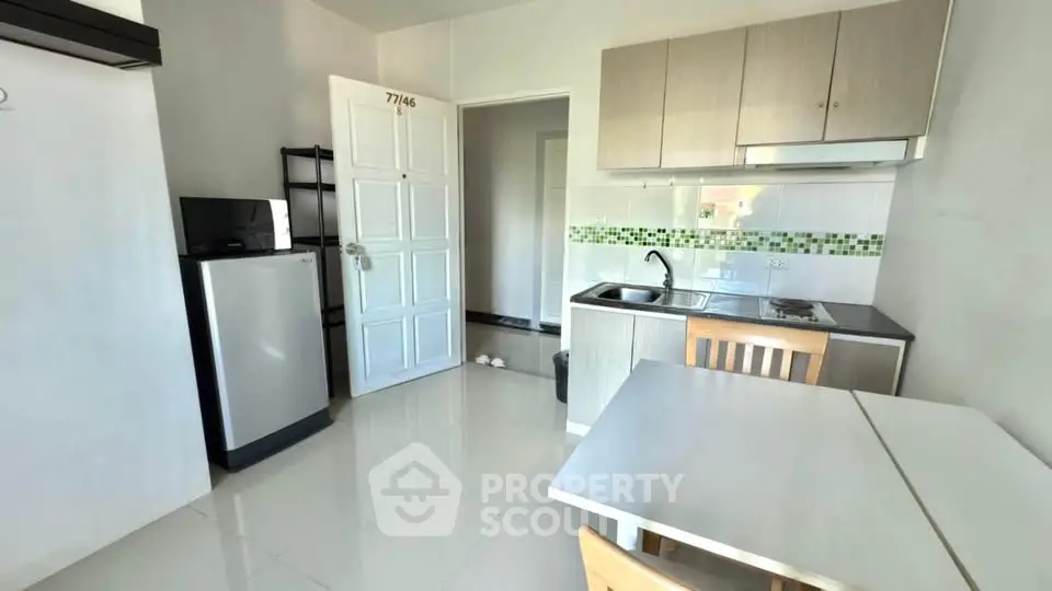 Modern compact kitchen with sleek cabinets and dining area in a bright apartment.