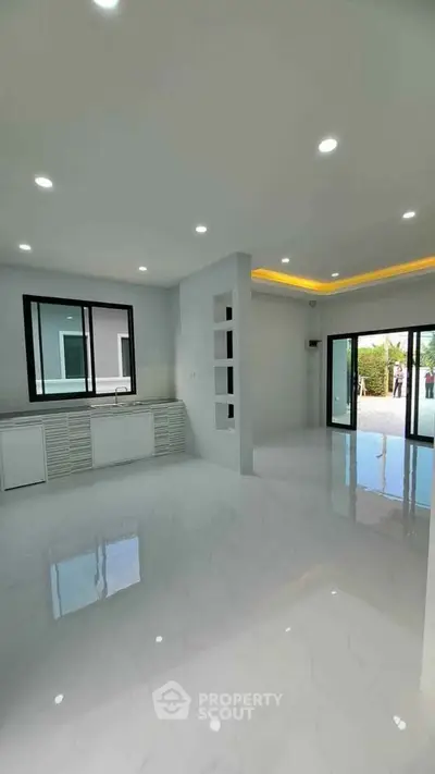 Spacious modern living area with sleek white flooring and large windows for natural light.