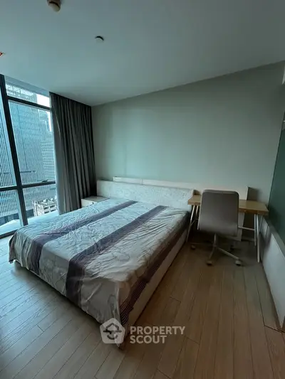 Modern bedroom with large window and study desk in urban apartment