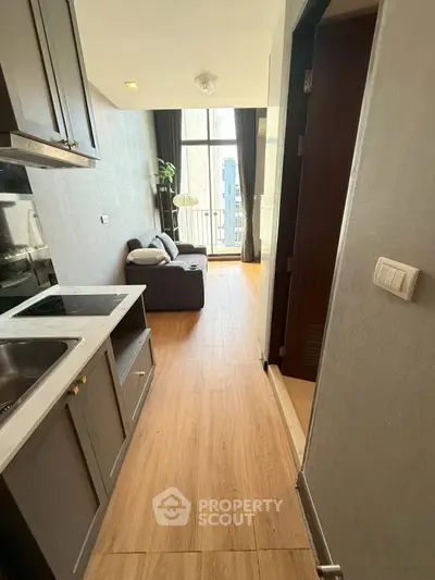 Modern apartment with open kitchen and cozy living area, featuring high ceilings and natural light.
