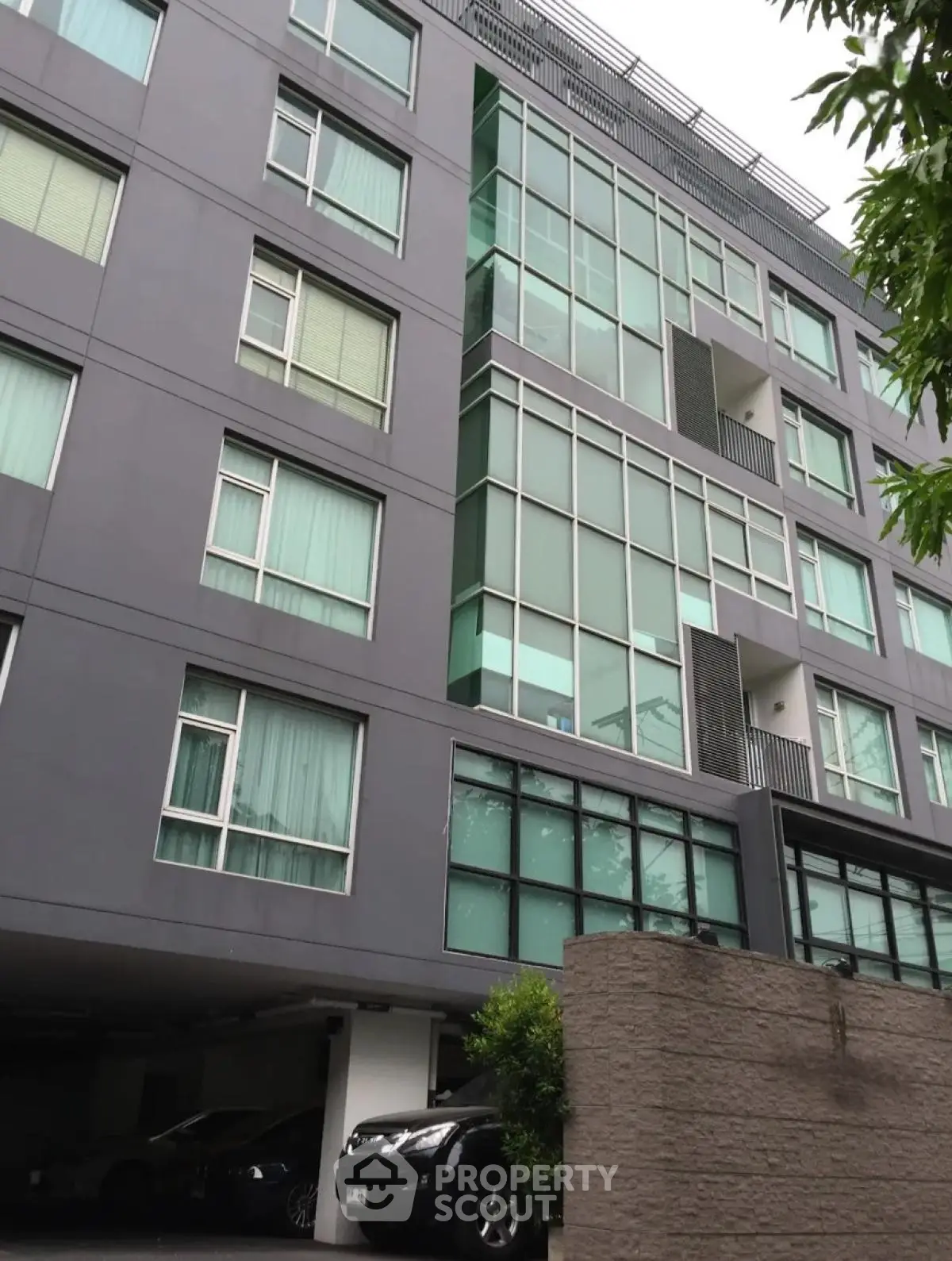 Modern apartment building with large windows and parking area, ideal urban living.