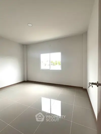 Spacious empty room with large window and glossy tiled floor, perfect for customization.