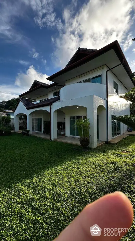 Stunning two-story house with lush green lawn and modern architecture under a clear blue sky.