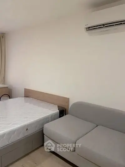 Modern bedroom with bed, sofa, and air conditioning unit.