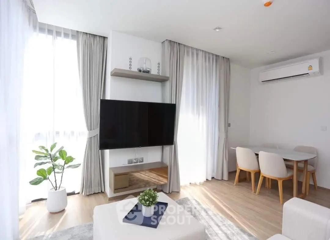 Bright modern living room with large TV, dining area, and stylish decor