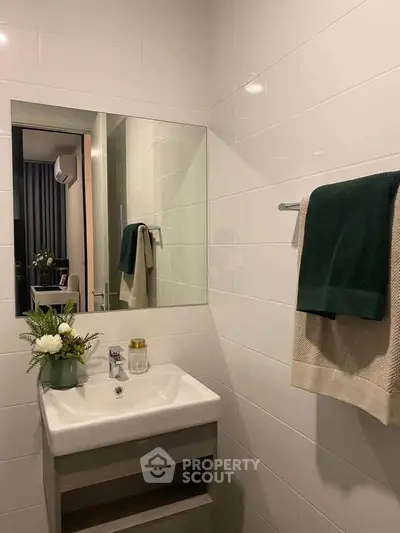 Modern bathroom with sleek sink and mirror, featuring elegant decor and towels.