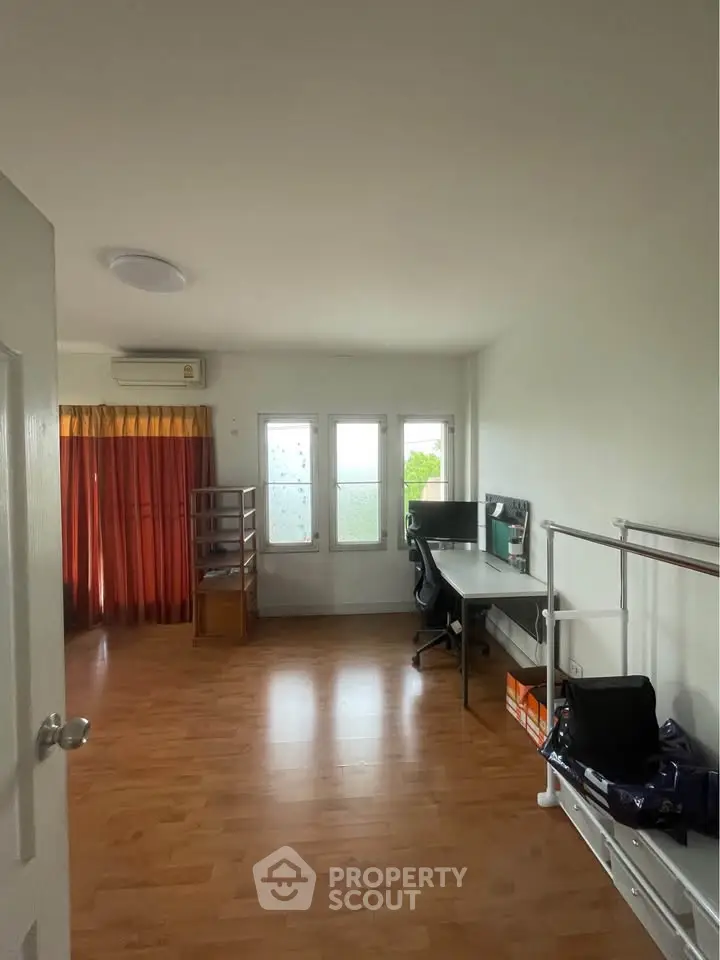 Spacious study room with wooden flooring and natural light, ideal for productivity.