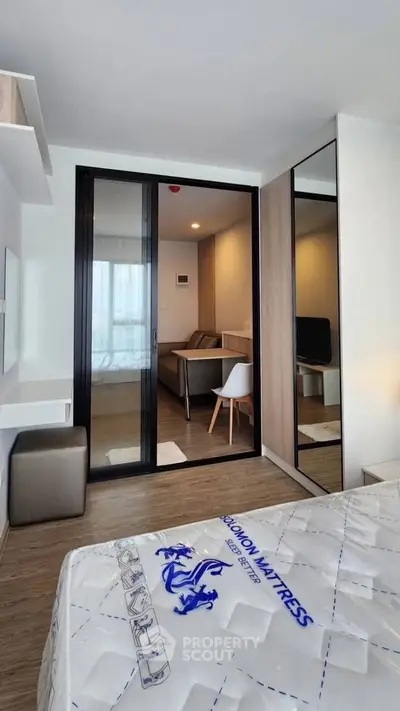 Modern bedroom with sliding glass doors leading to a cozy living area, featuring stylish furniture and natural light.