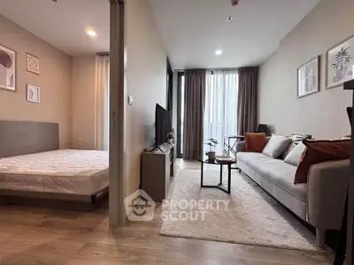 Modern open-plan living room with cozy sofa and adjacent bedroom in stylish apartment.