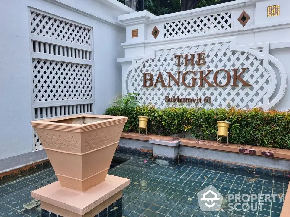 Elegant entrance of The Bangkok Sukhumvit 61 with decorative fountain and lush greenery.