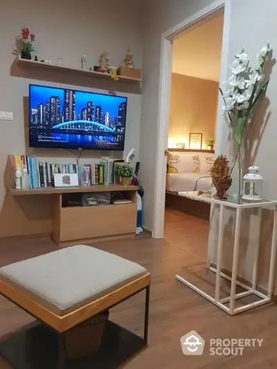 Cozy living room with modern furnishings, wall-mounted TV, and a well-organized bookshelf creating a welcoming atmosphere for relaxation and entertainment.