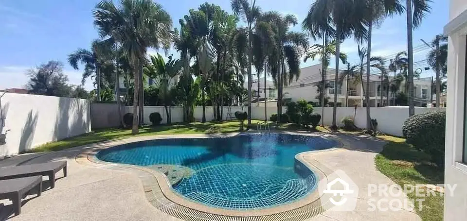 Luxurious private pool surrounded by lush palm trees in a serene residential setting