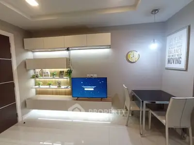 Modern living room with sleek TV unit and dining area, featuring stylish decor and ambient lighting.